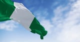 Nigerian flag waving in the wind against a blue sky