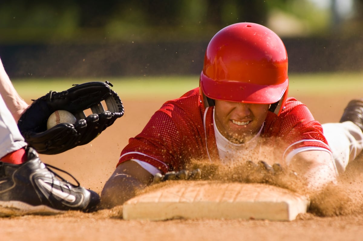 Baseball player sliding into base on a dirt field during a game